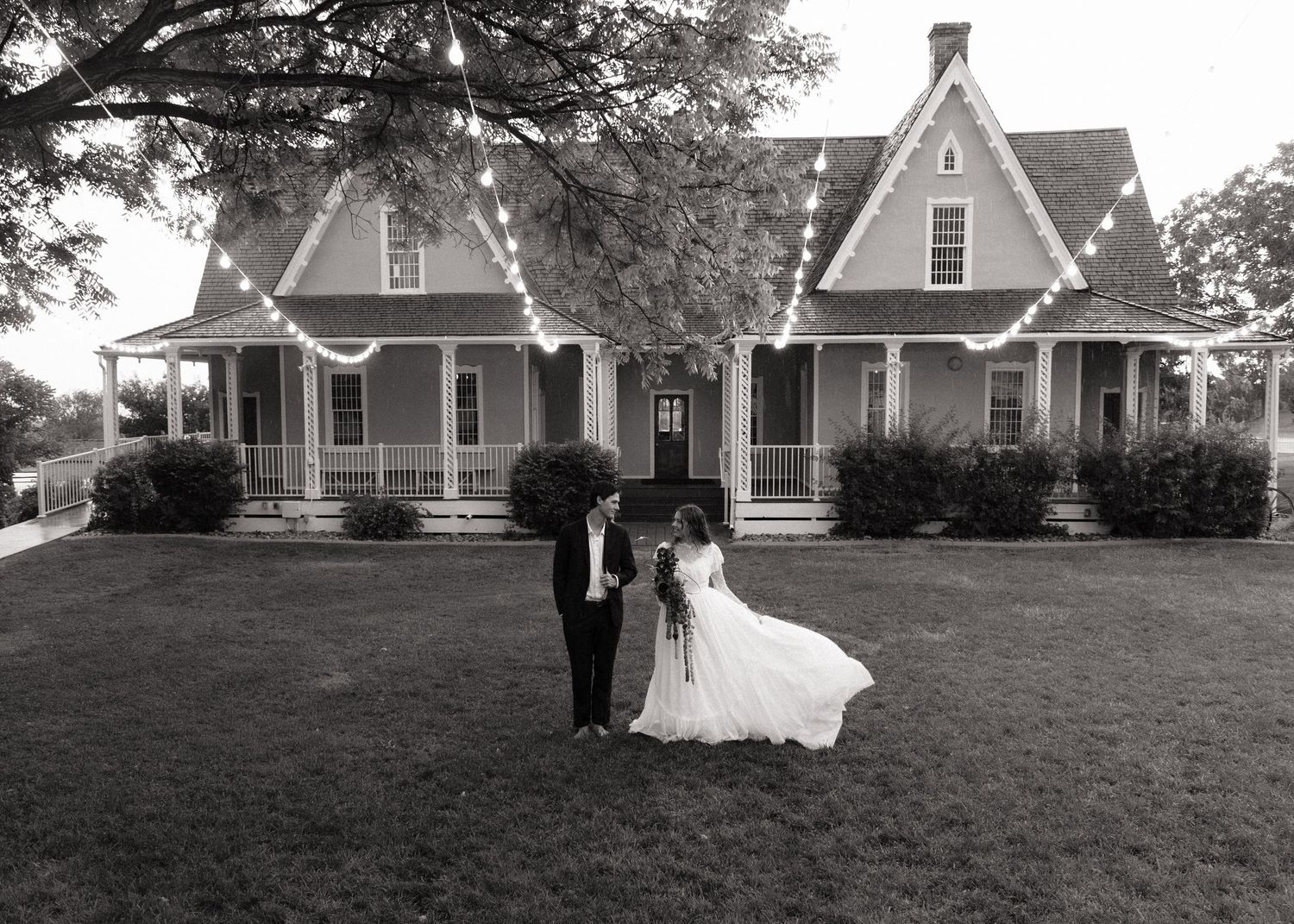 Bride and groom outside a historic home at their Utah wedding, photographed in black and white.