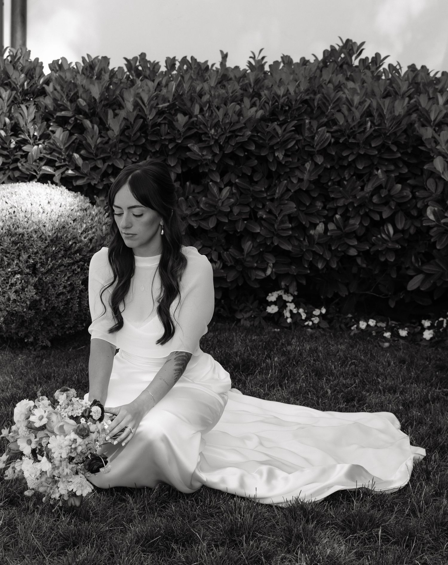 Black and white bridal portrait of a bride seated in a garden at a Utah wedding.