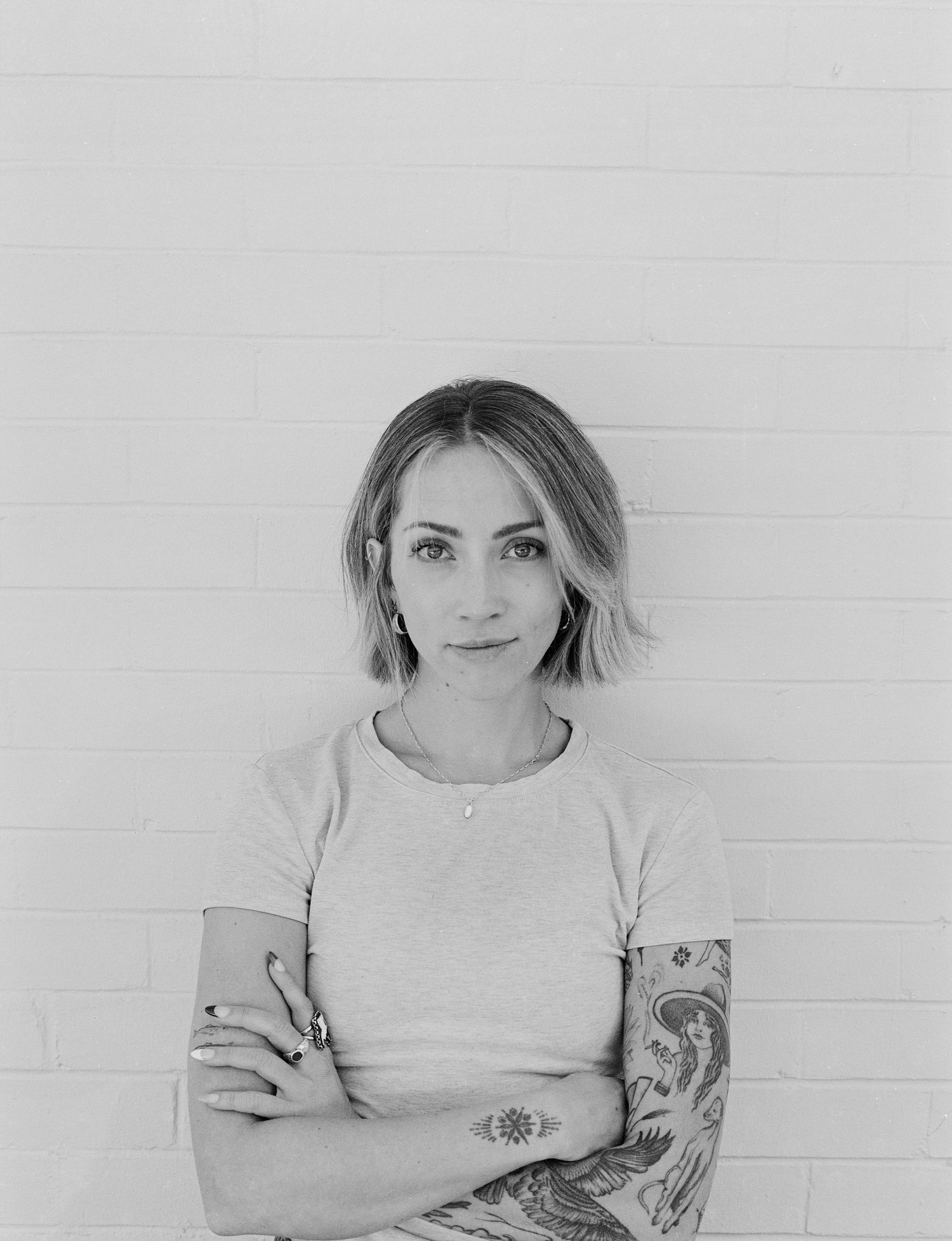 Black and white film portrait against a white brick wall in Salt Lake City, Utah.