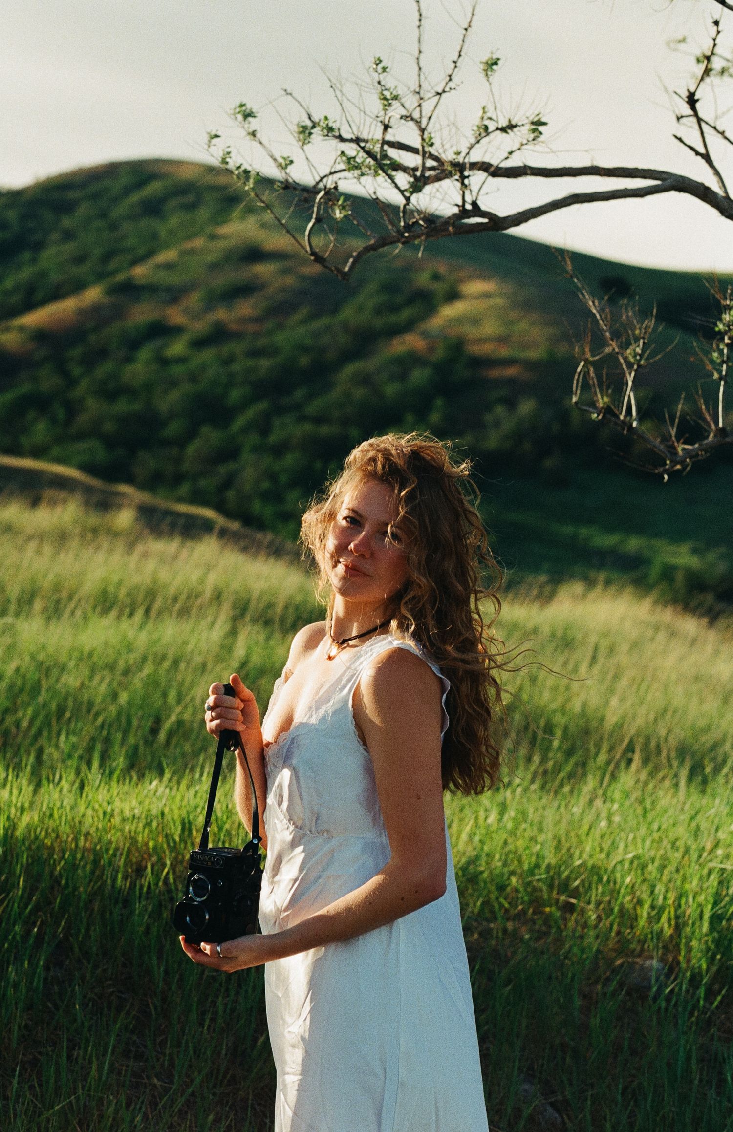 35mm film portrait of a woman in a green field in the Utah mountains.