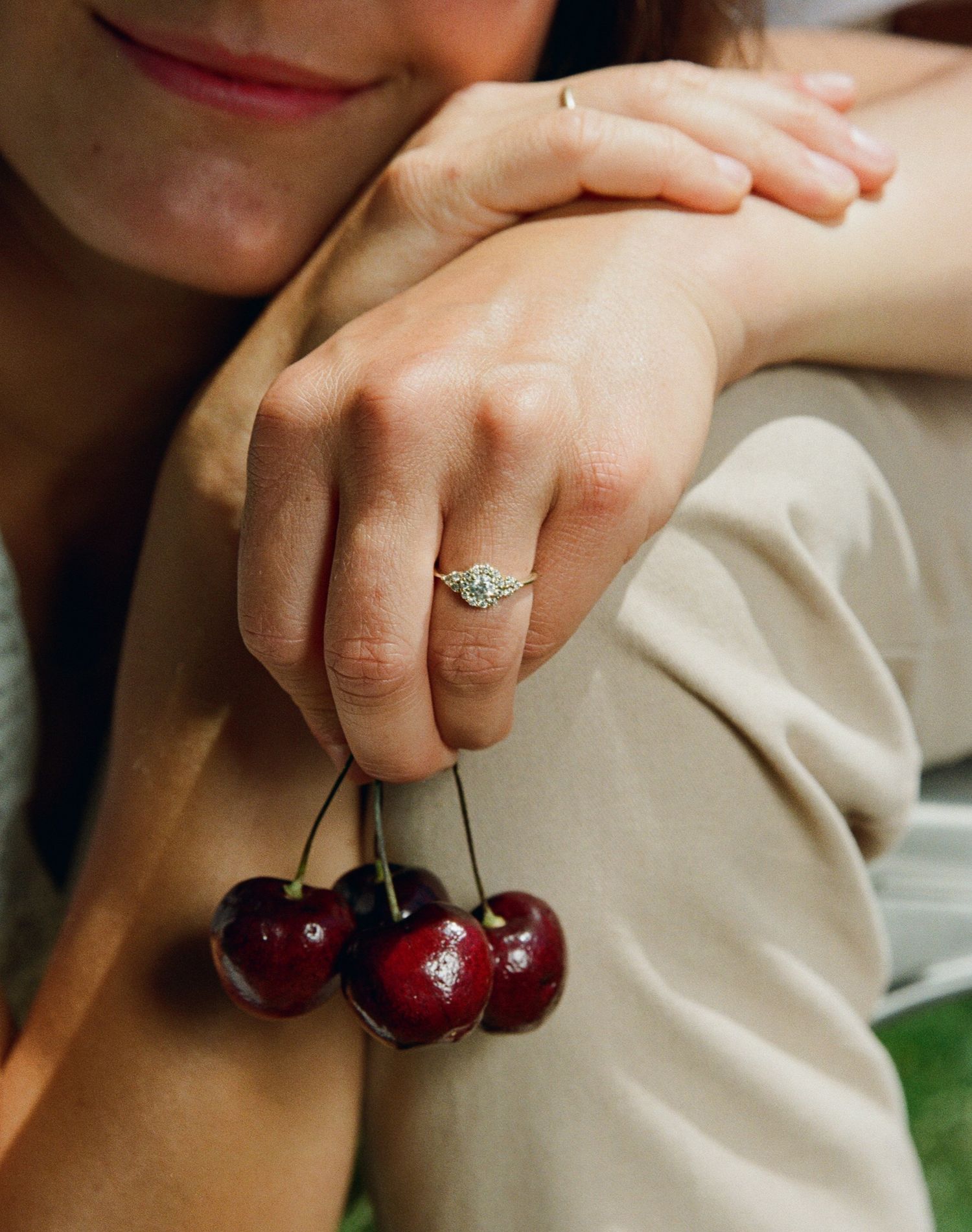 Engagement ring detail with cherries, photographed on film in warm natural light.