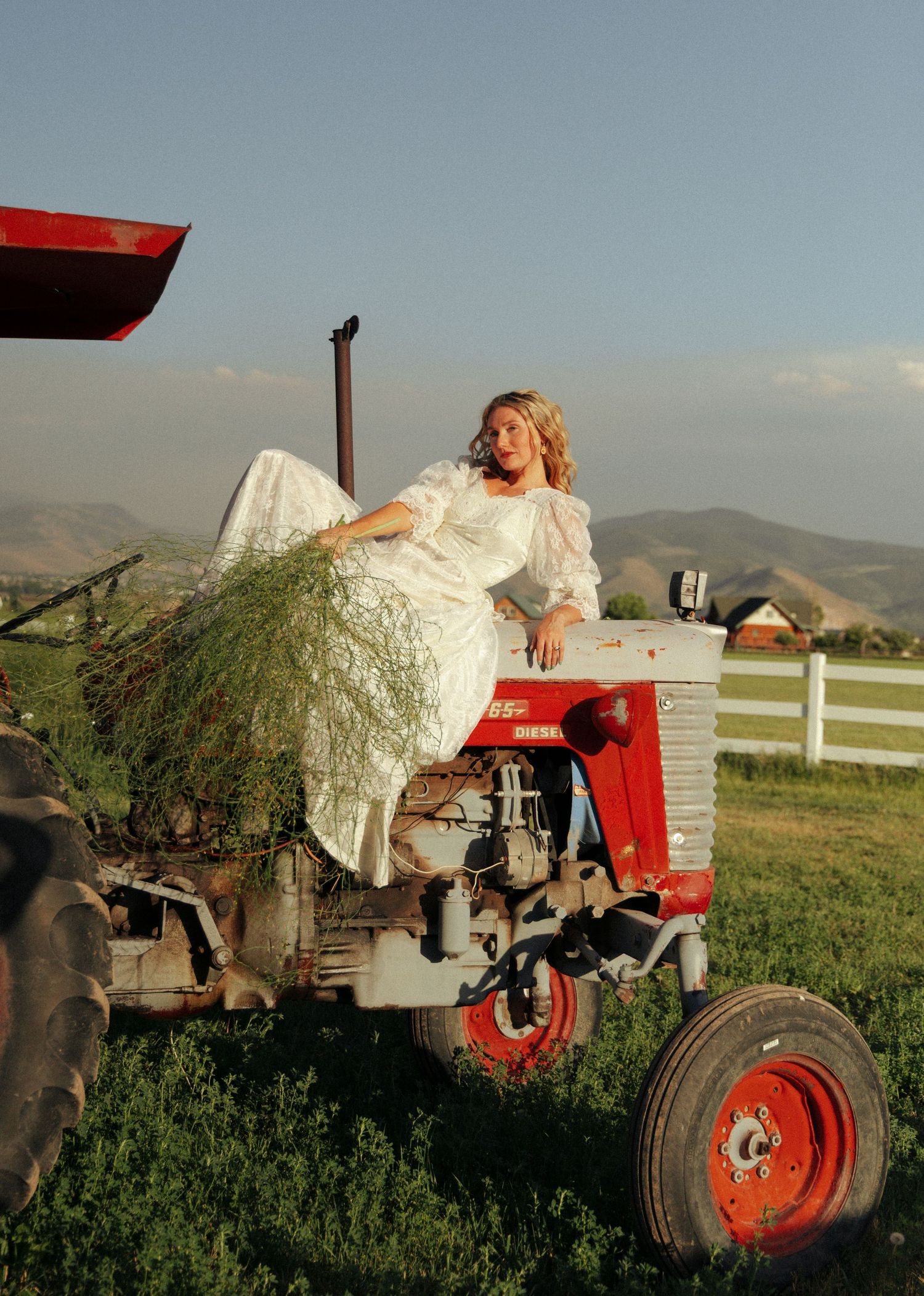 Editorial bridal portrait on a vintage tractor surrounded by Utah farmland.