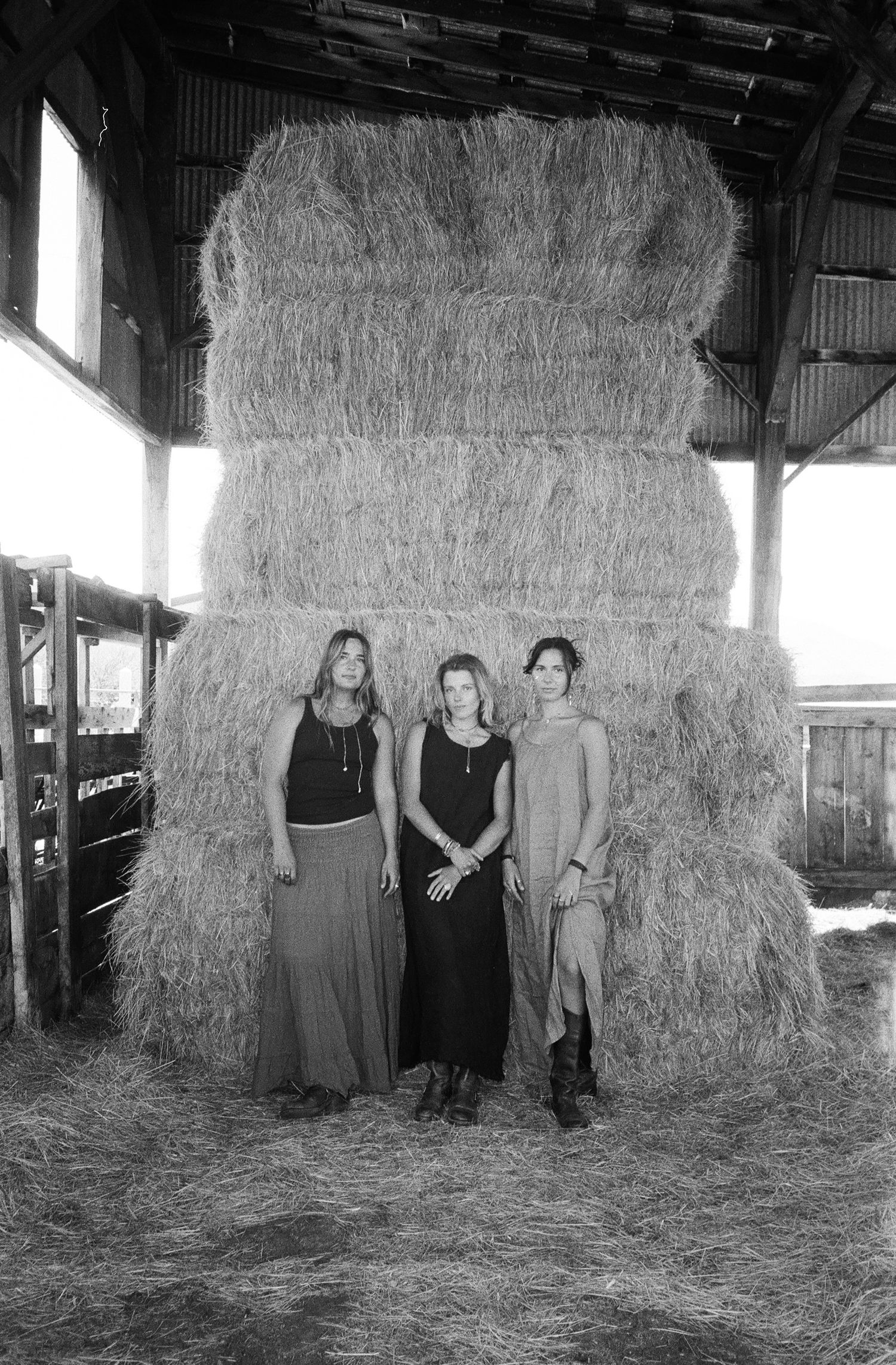 Black and white 35mm film portrait of three women inside a rustic Utah barn.