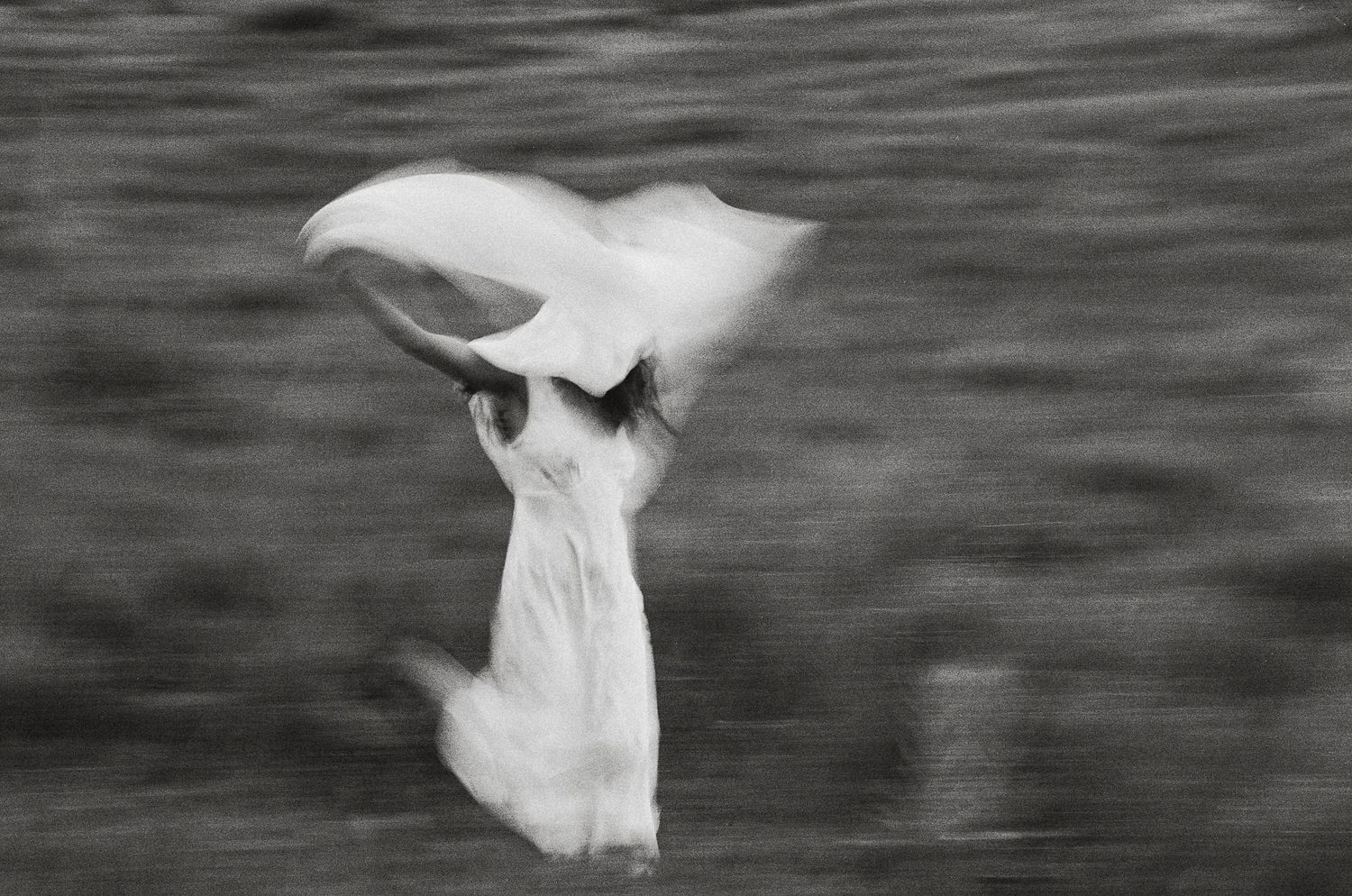 Black and white 35mm film portrait of a woman running through a field with motion blur in Utah.