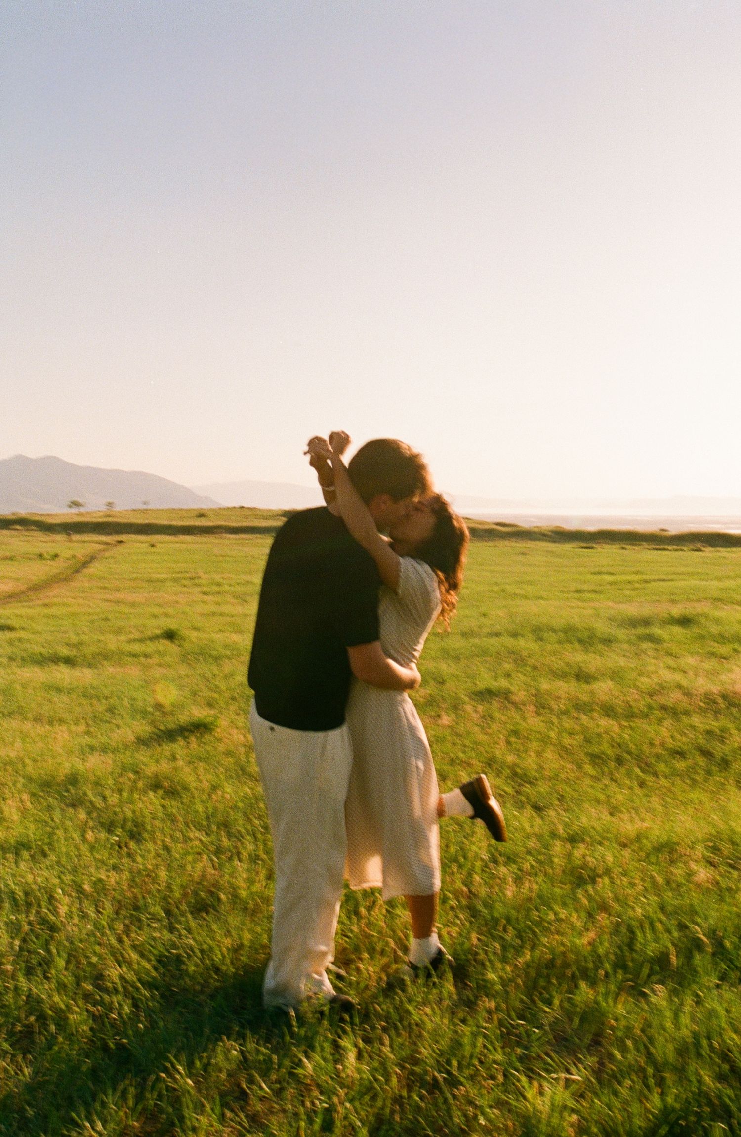 35mm film couples portrait embracing in a sunlit field in Utah.