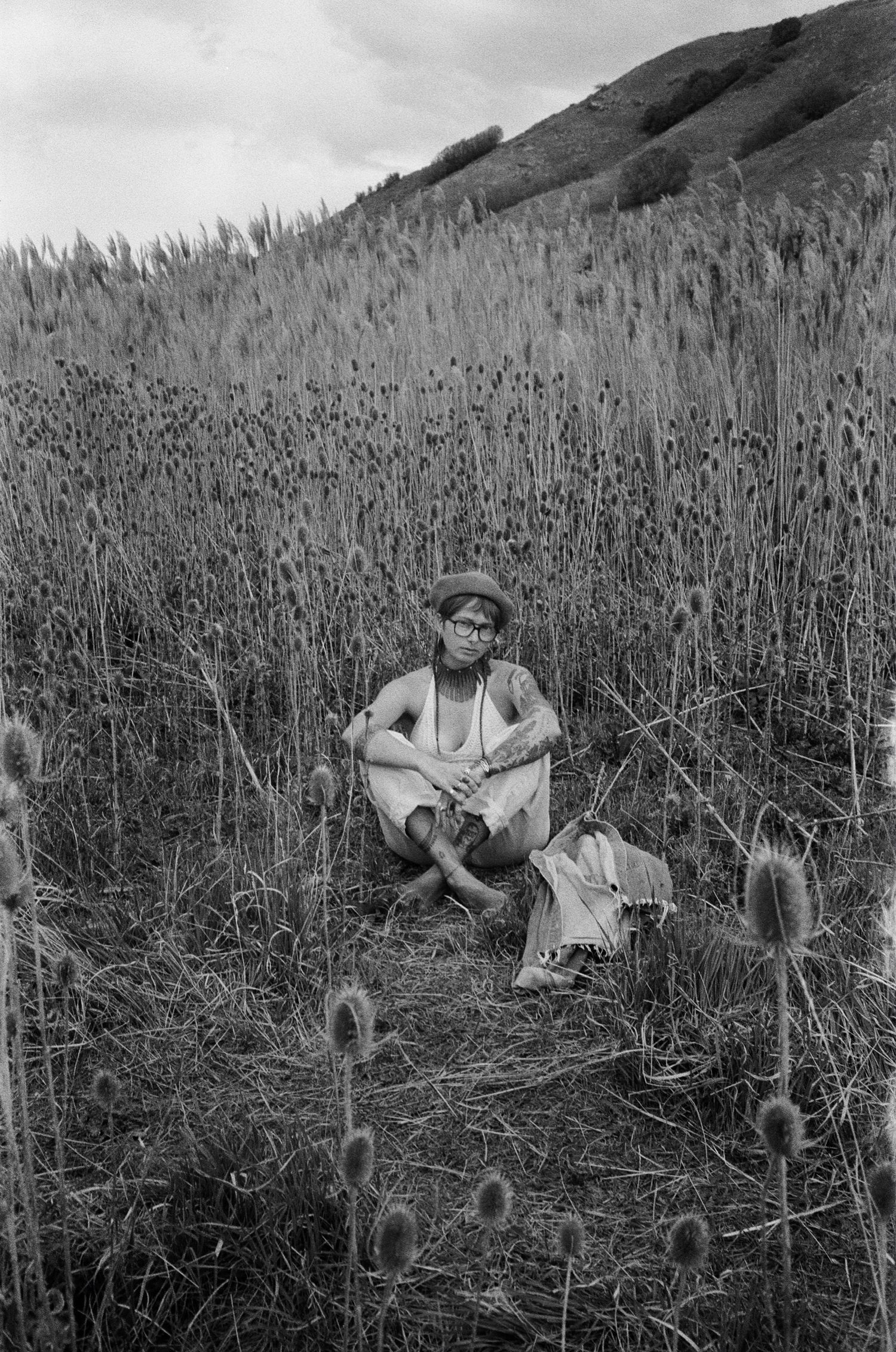 Black and white film portrait of a woman seated among tall grasses in the Utah landscape.