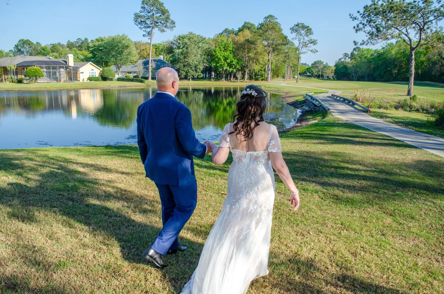 Bride and Groom take a stroll by the lake during their formal photos at DeerCreek Country Club.