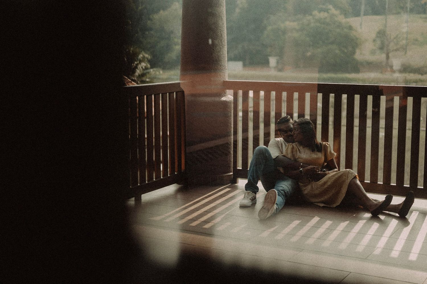 Couple sitting closely together on a wooden porch in a candid romantic moment.