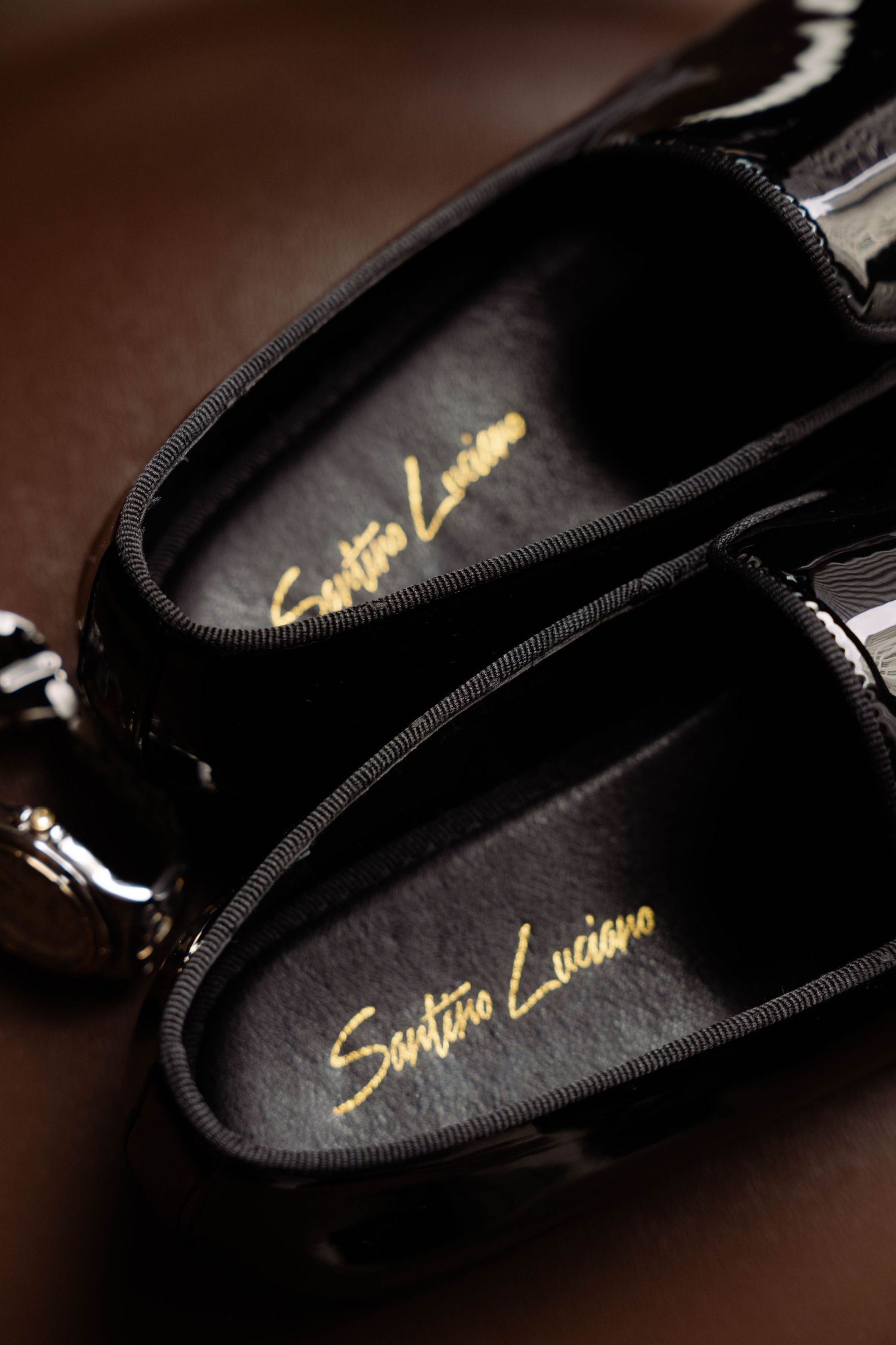 Luxury Santino Luciano black patent leather dress shoes with gold script logo.