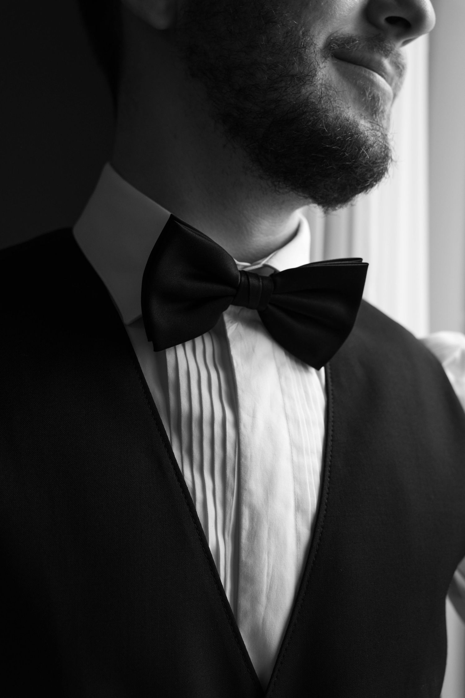 Black and white close-up of a bearded groom in a tuxedo with a bow tie.