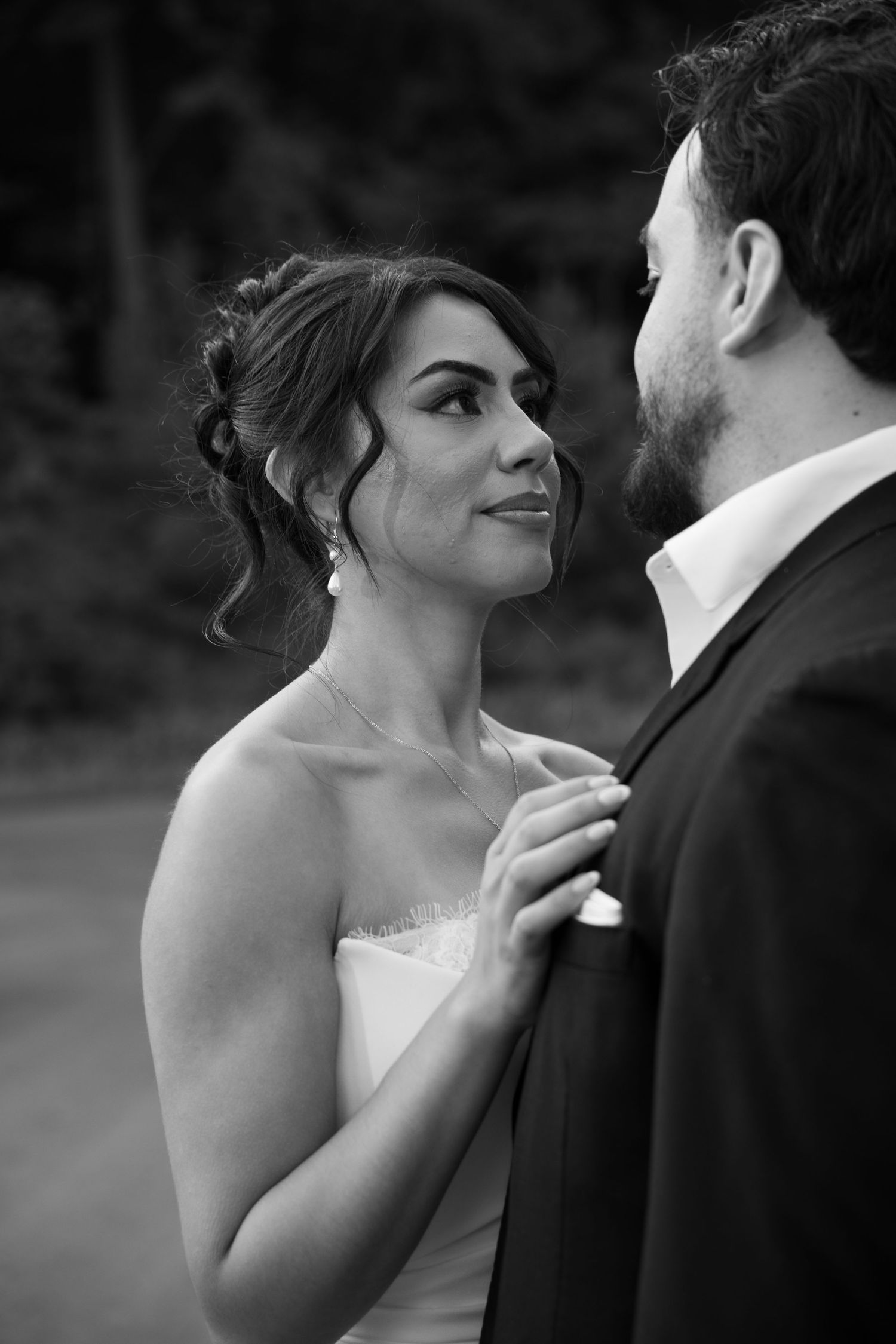 Bride gazes lovingly at groom in a stunning black and white wedding portrait outdoors.