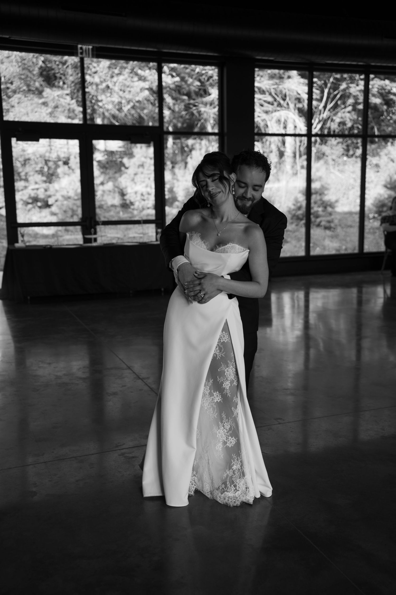 Bride in strapless lace wedding gown dances with groom in black and white romantic wedding reception photo.