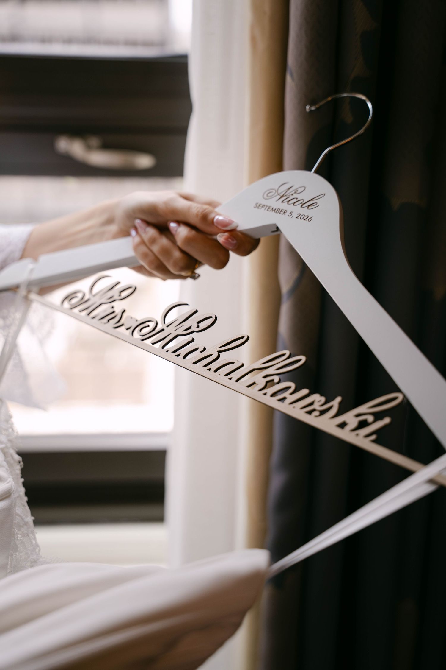 Bride holding a custom wooden wedding dress hanger engraved with Mrs. Minhalcowski and September 5, 2025.