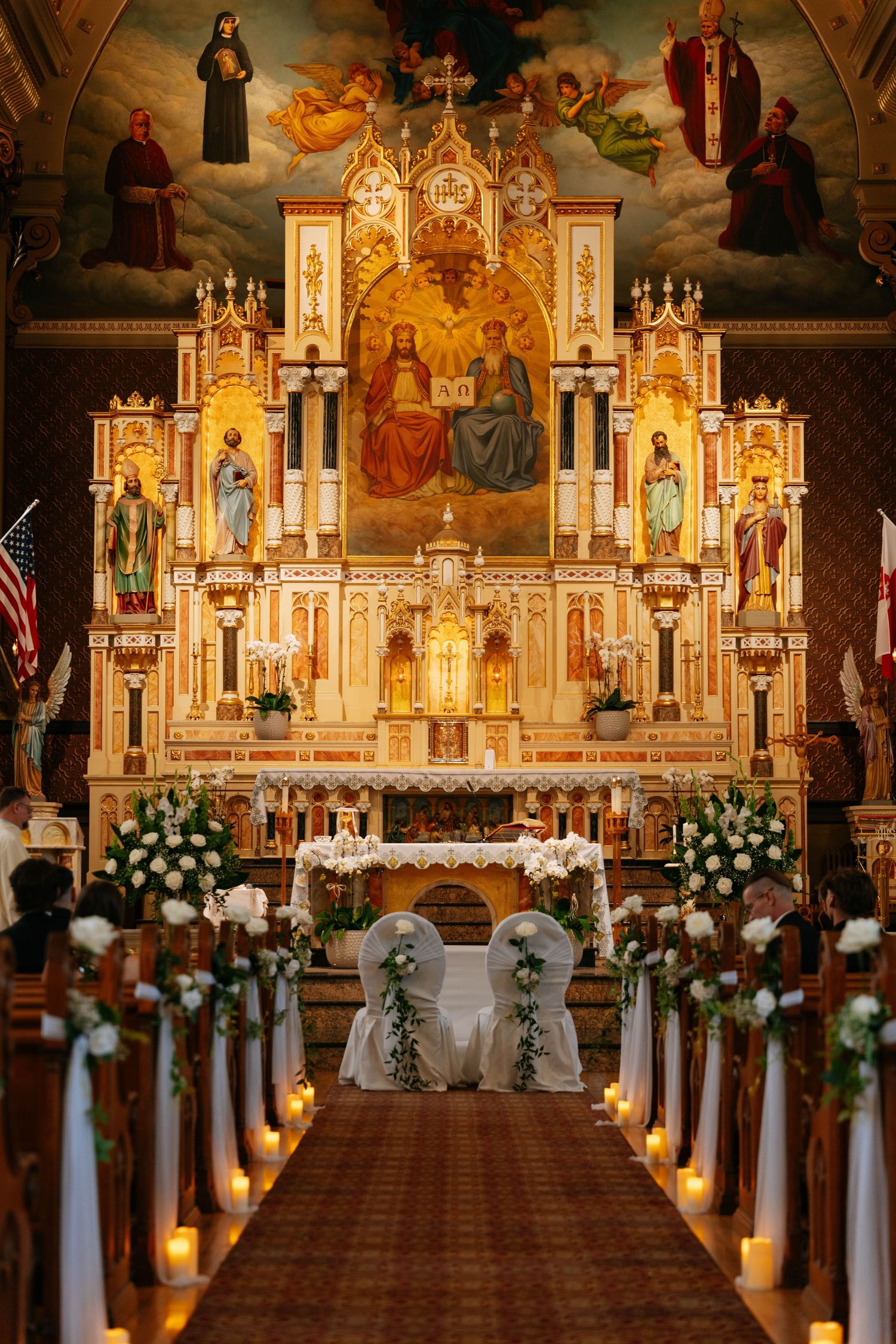Ornate church altar decorated with candles and white flowers for wedding ceremony.