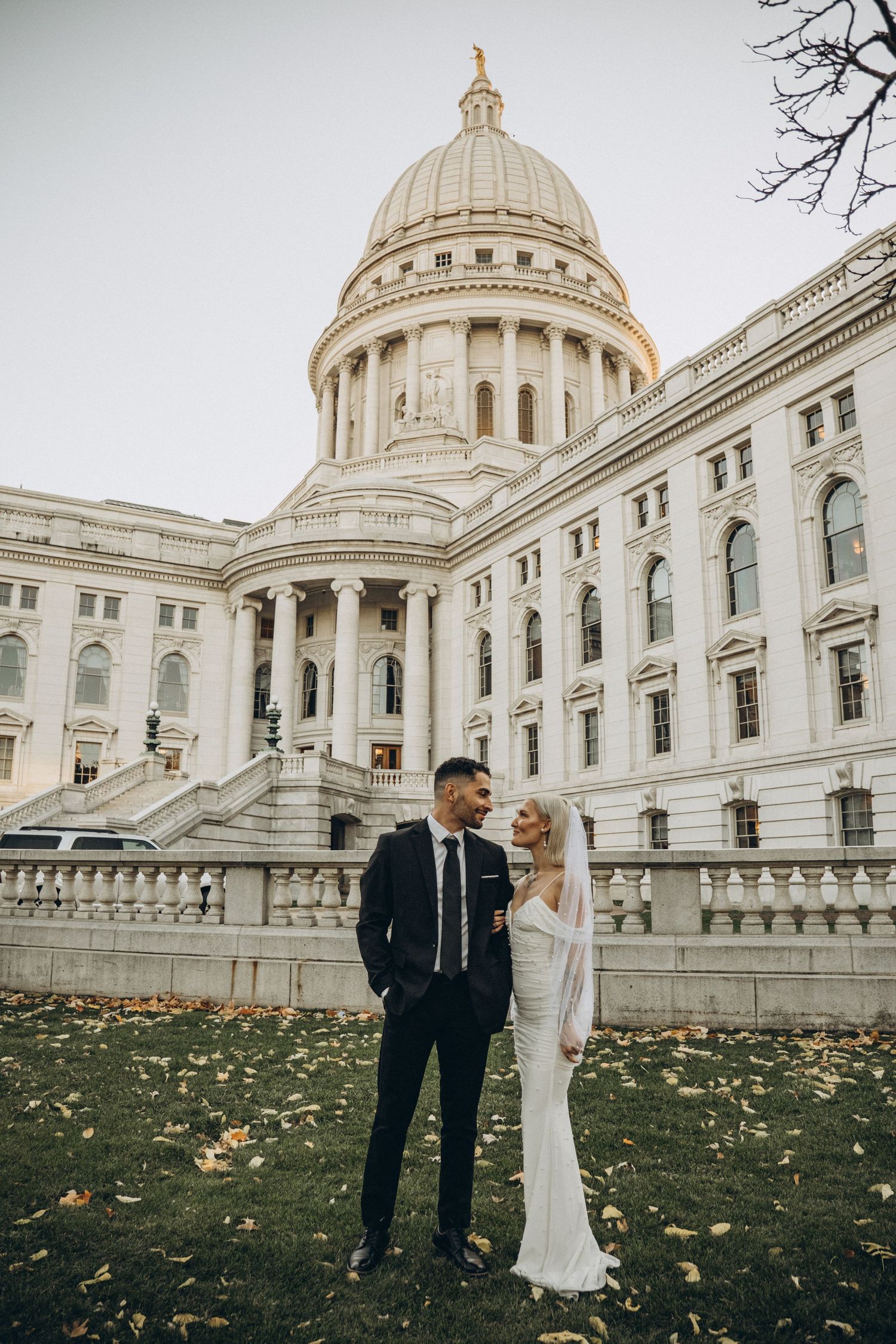 Bride and groom pose together in front of the Wisconsin State Capitol building dome during their wedding day.
