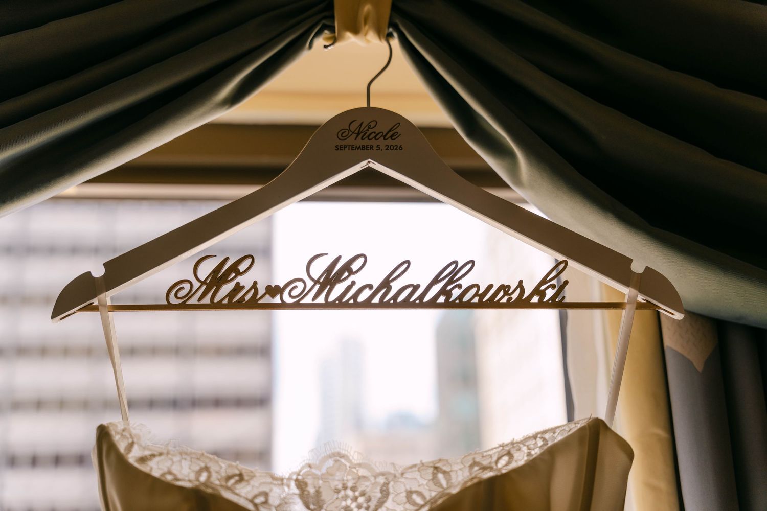 Personalized wooden wedding hanger reading Mrs. Michalkowski displayed with elegant bridal gown in soft window light.