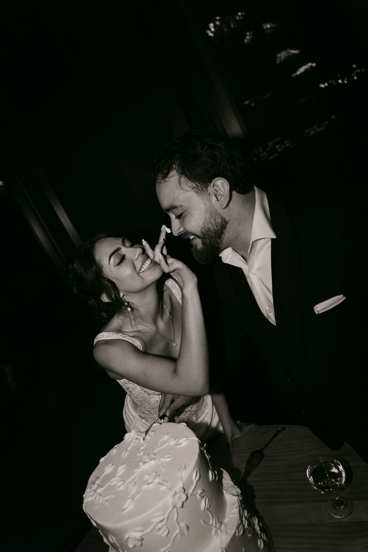 Black and white intimate photo of laughing bride and groom sharing a tender moment at wedding.