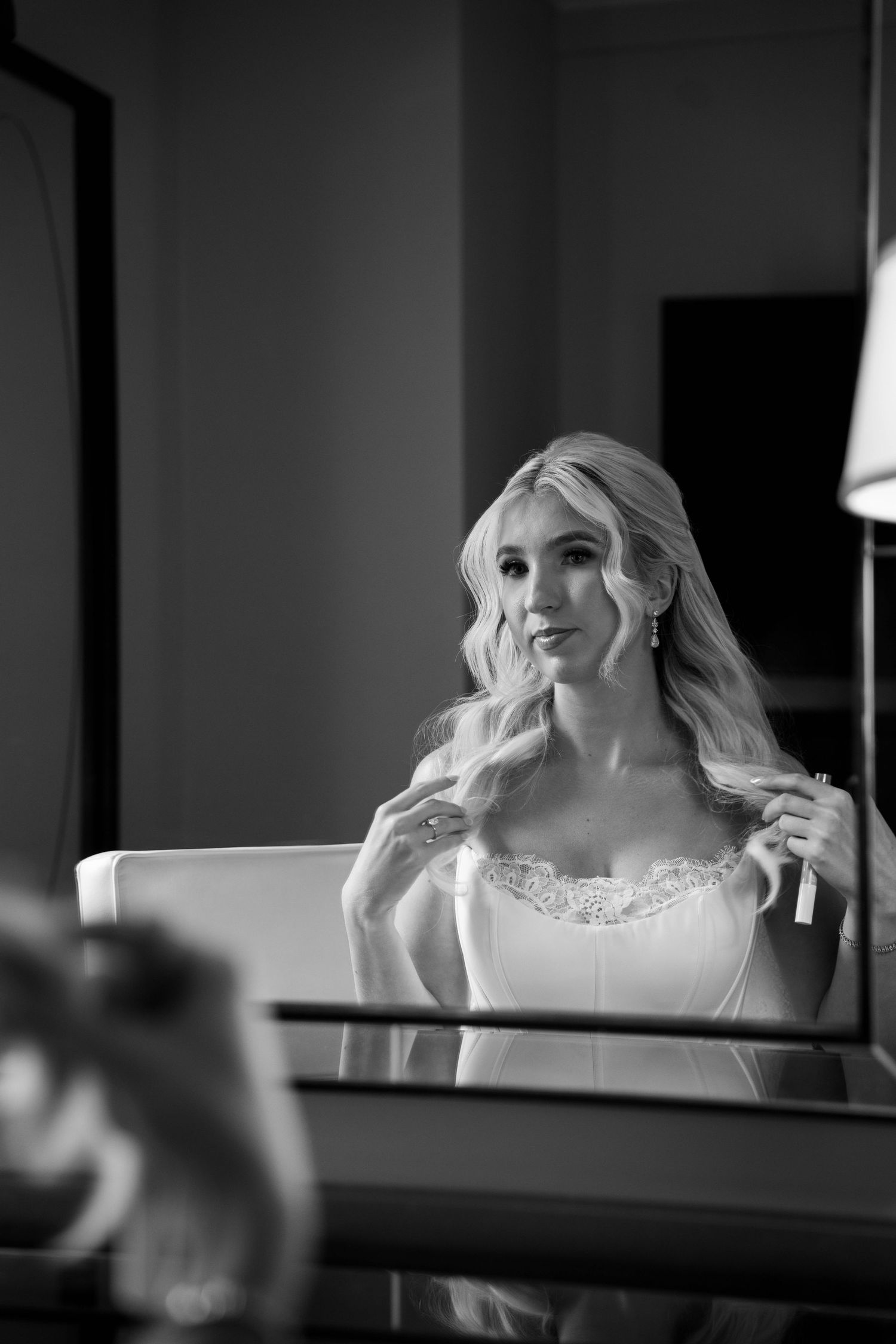 Black and white portrait of blonde bride in wedding dress at mirror.