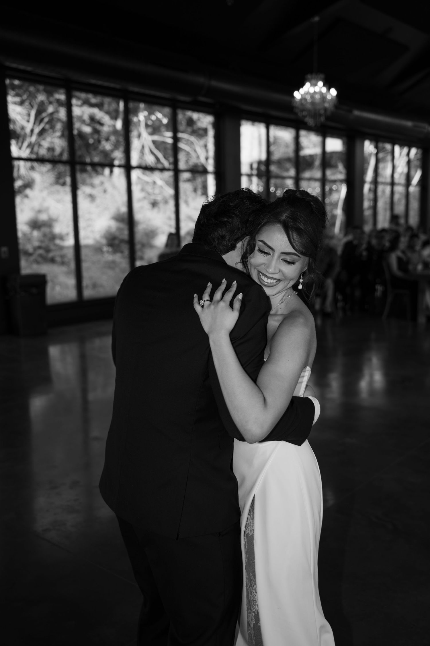 Bride and groom share an intimate first dance embrace, smiling joyfully in a black and white wedding photo.