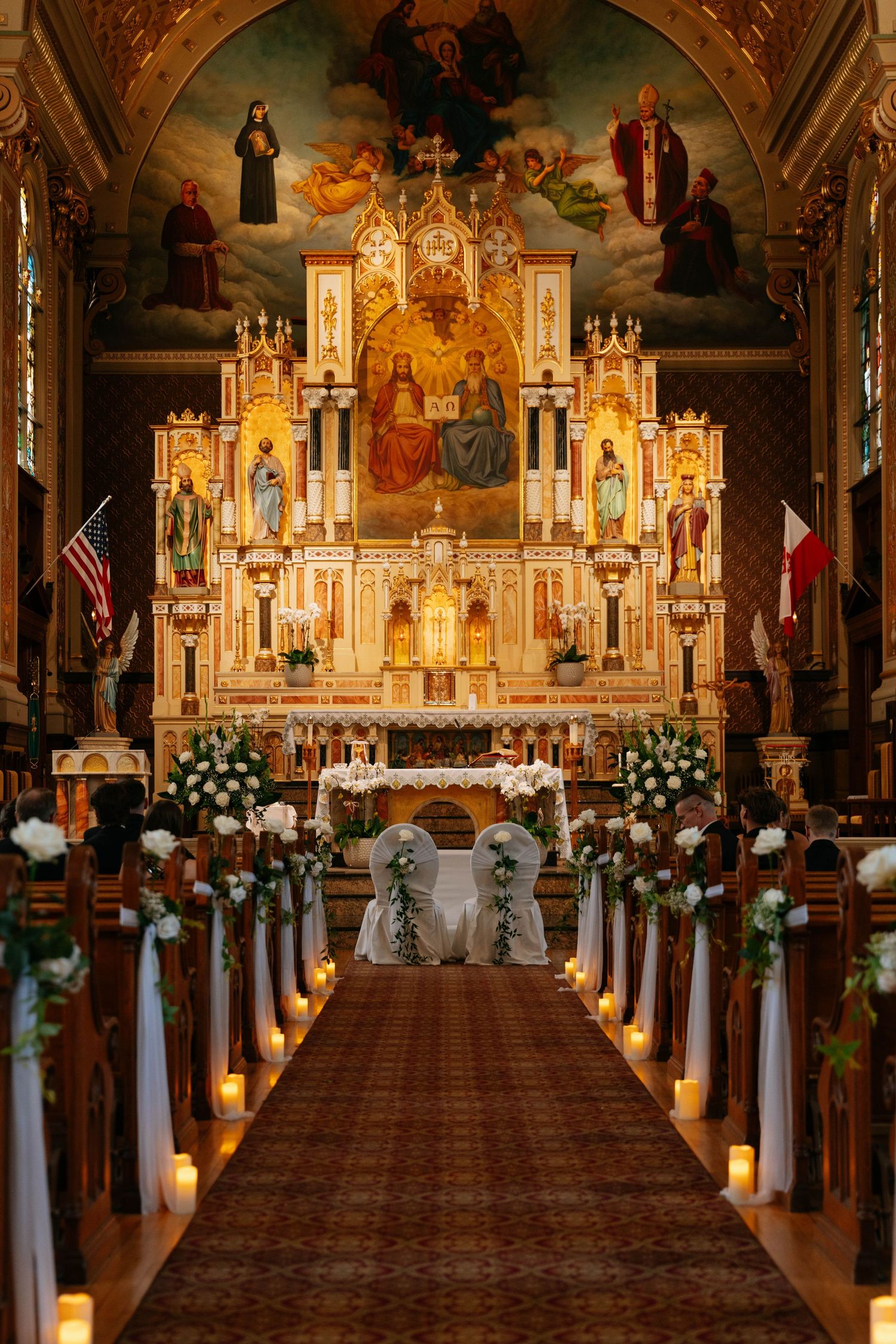 Ornate Catholic church altar decorated with white flowers and candles for an elegant wedding ceremony.