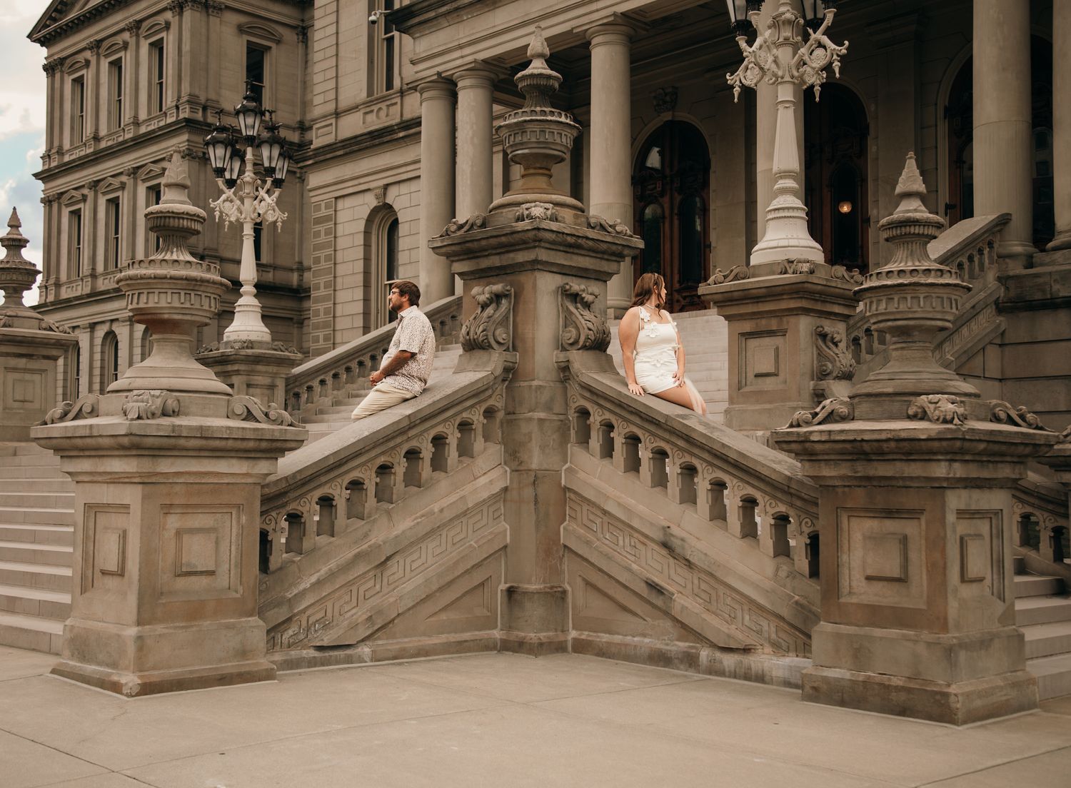 Couple poses on ornate stone staircase of historic government building with classical architecture.