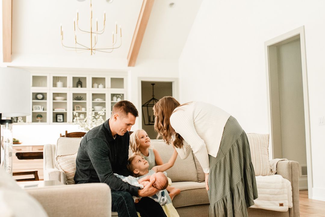 A happy family with two young children shares a joyful moment together in a bright, modern living room.