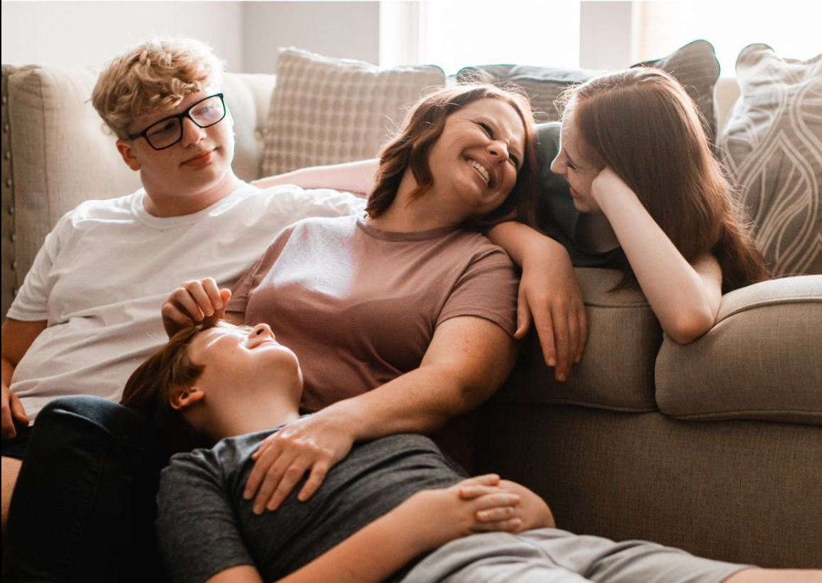 A joyful family of four relaxing together on a cozy couch, laughing and bonding in a warm living room.