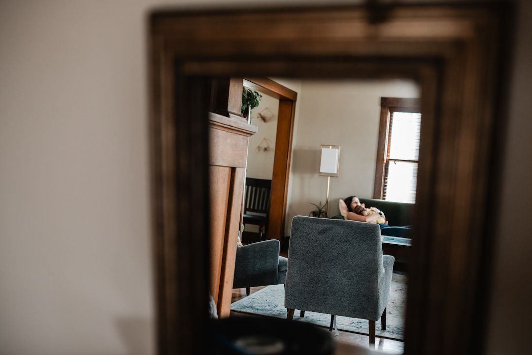 Cozy living room reflected in vintage wooden mirror with blue accent chairs.