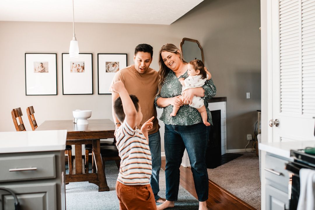 Family of four sharing a joyful moment together in a bright modern home.