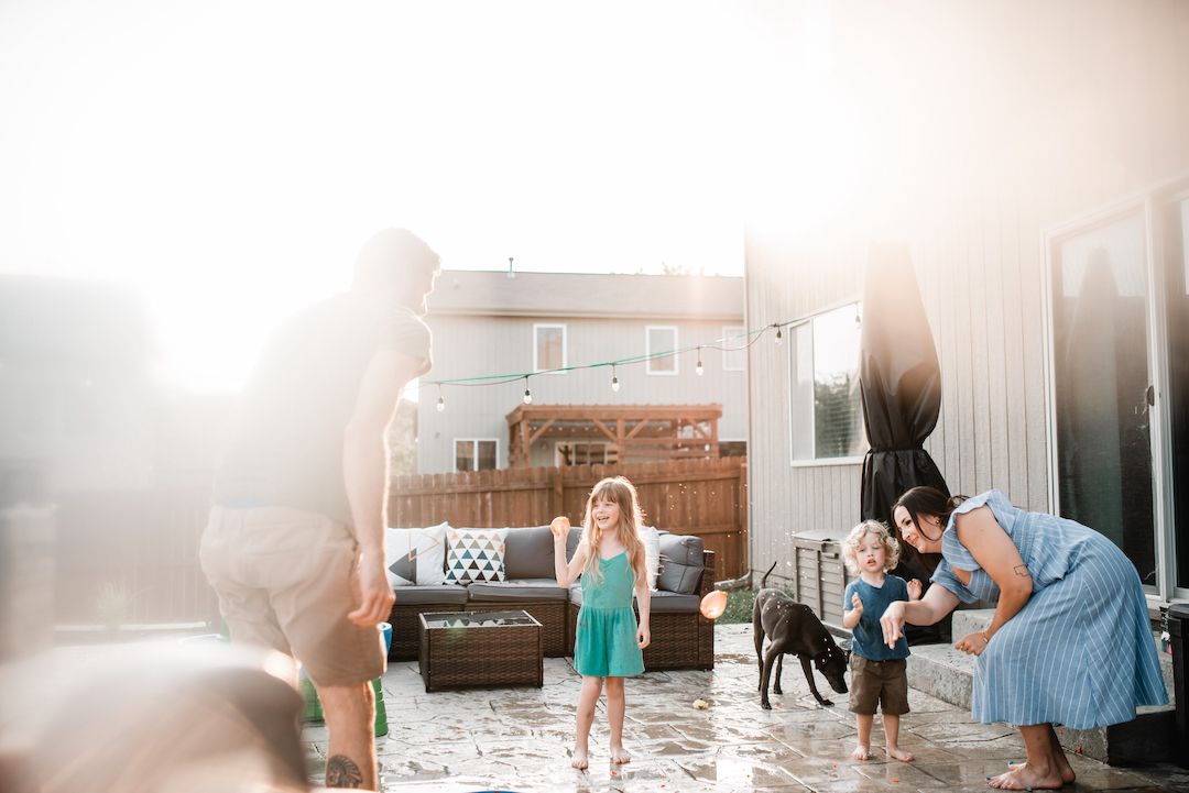 Family enjoying a sunny outdoor patio with kids and a dog in bright natural light.