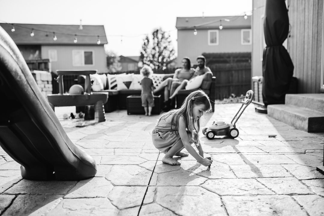 Black and white photo of children playing on backyard patio with slide.