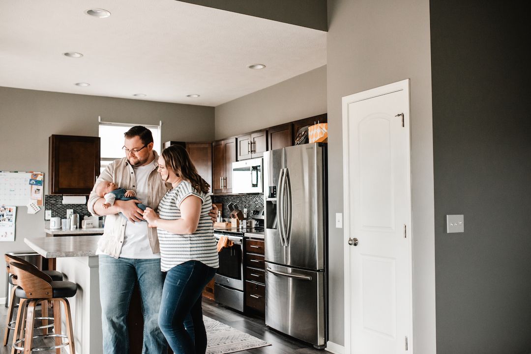 Couple embracing in a modern kitchen with stainless steel appliances.
