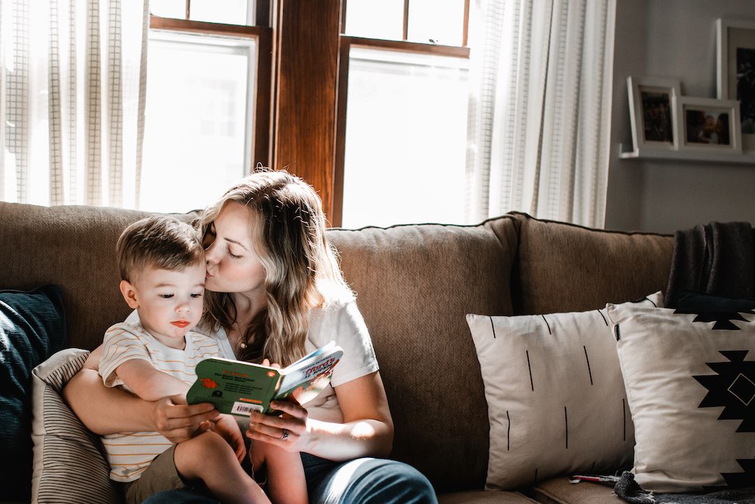 Mother and young son sitting on a couch together looking at a tablet screen.