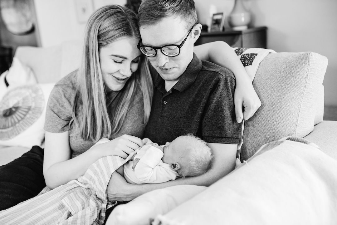 Happy young parents smiling at their newborn baby in black and white photo.