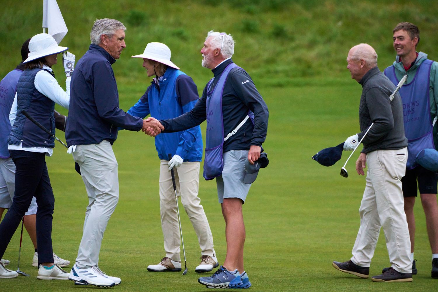 Golfers shaking hands on a links golf course fairway after completing their round.