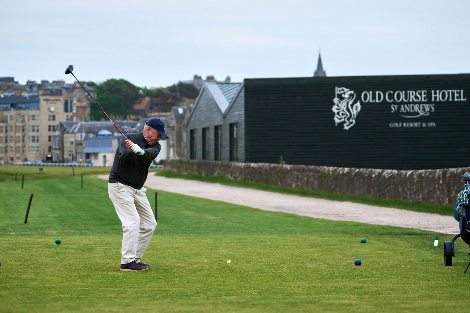 Golfer swinging at the Old Course Hotel St Andrews golf resort on a cloudy day.