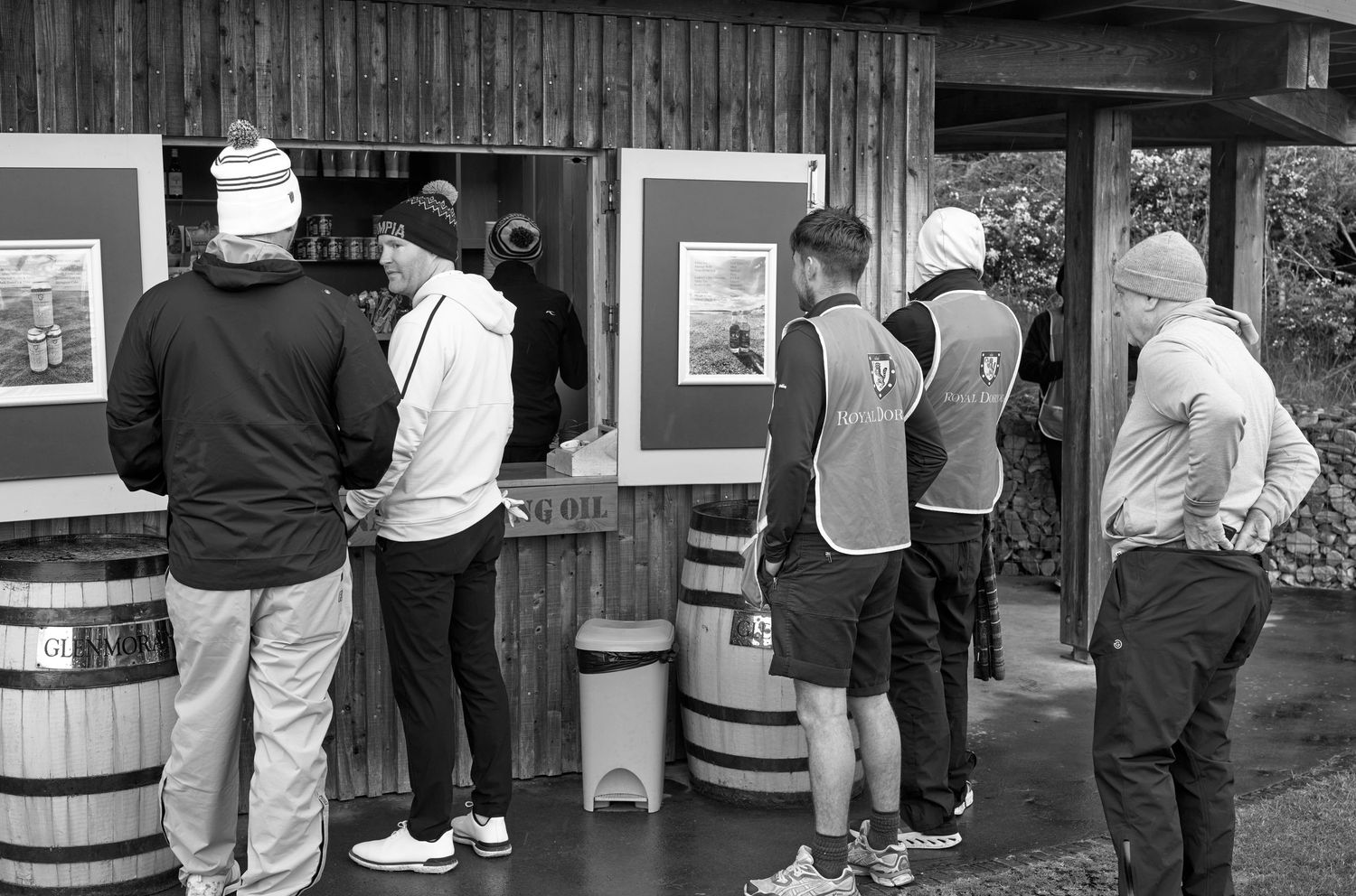 Black and white photo of golfers gathered at an outdoor refreshment stand on a golf course.
