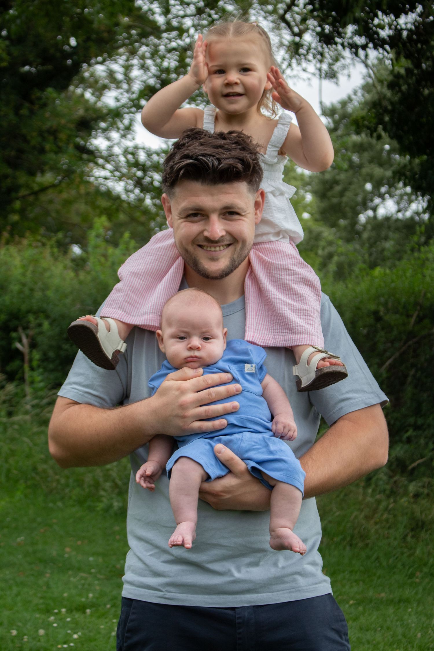 parent holding children in outdoor photography session.