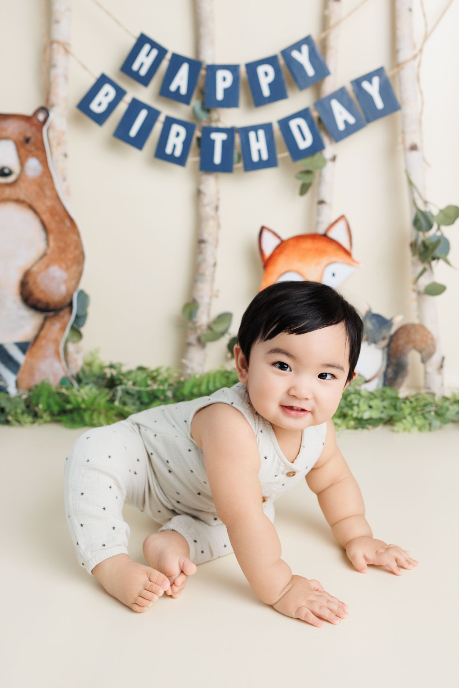 First birthday party setup with woodland theme decorations including blue banner, painted bear and fox wall art.