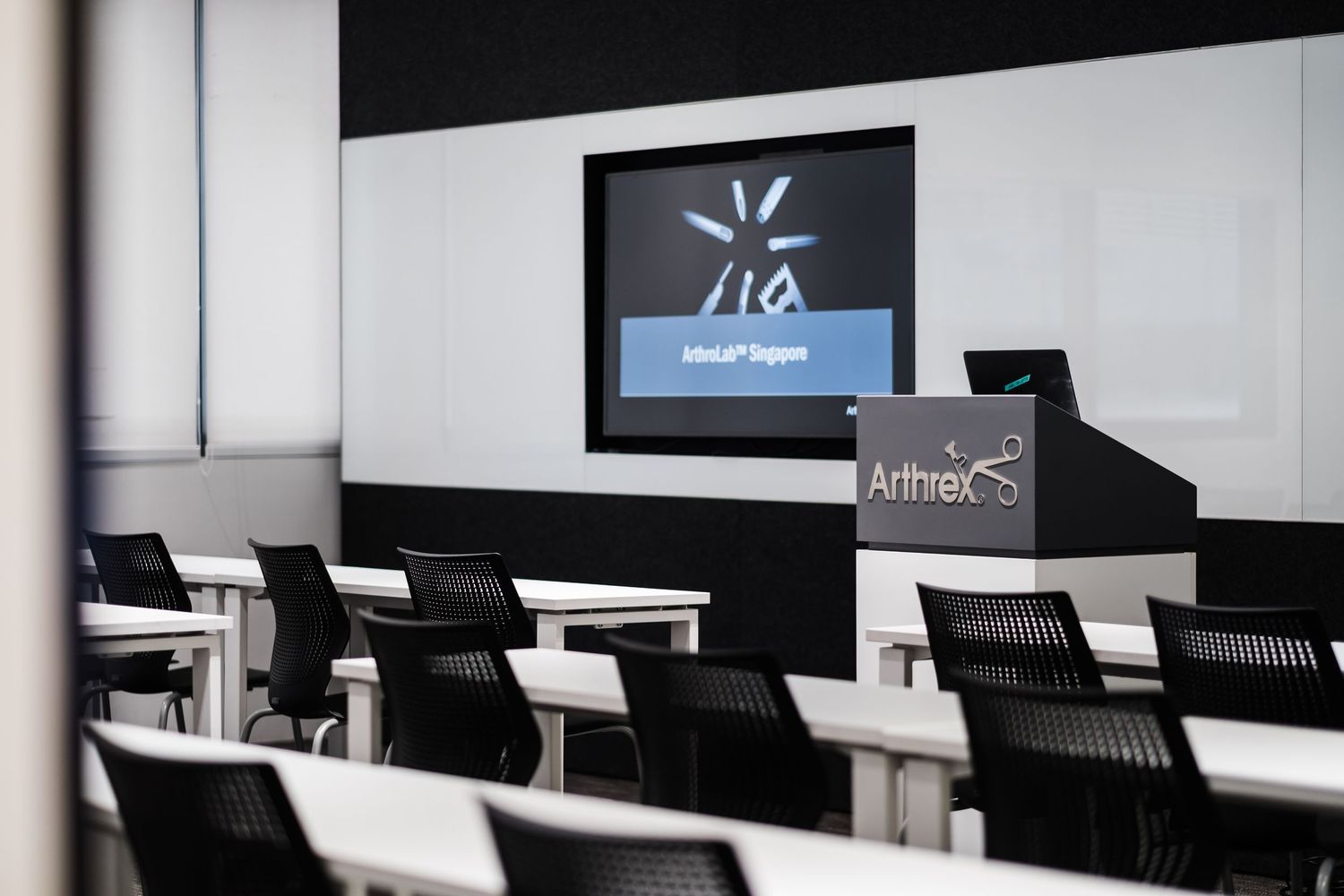 Contemporary office interior with black chairs and digital displays mounted on white walls.