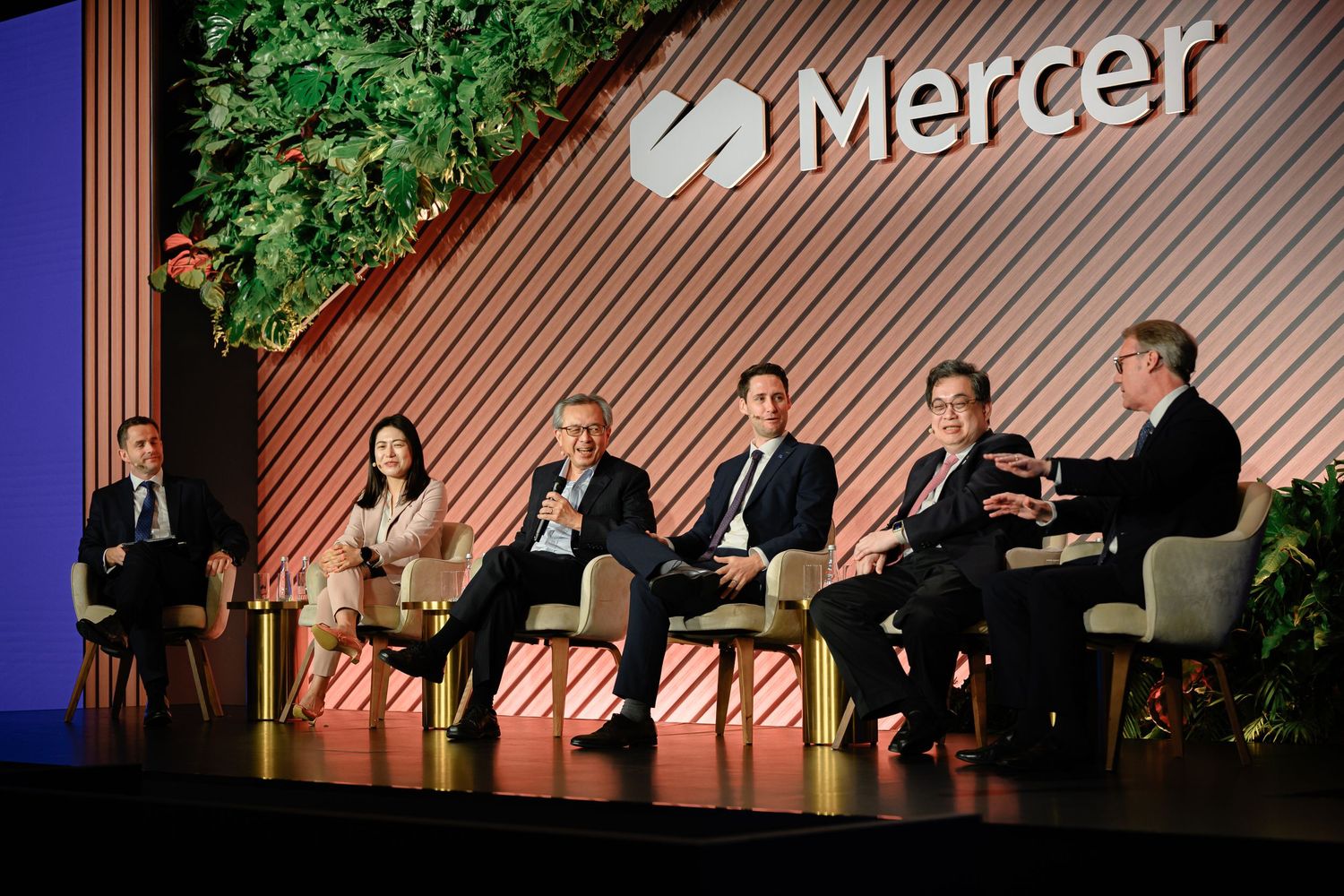 Business conference stage with panelists seated at a table during a Mercer event.