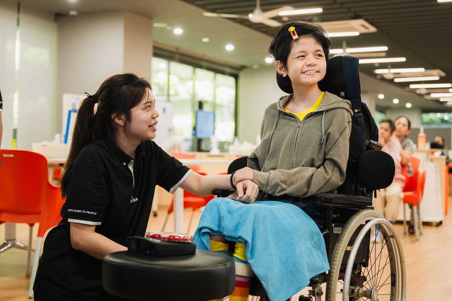 Healthcare professional and wheelchair user sharing a positive interaction in a medical setting.