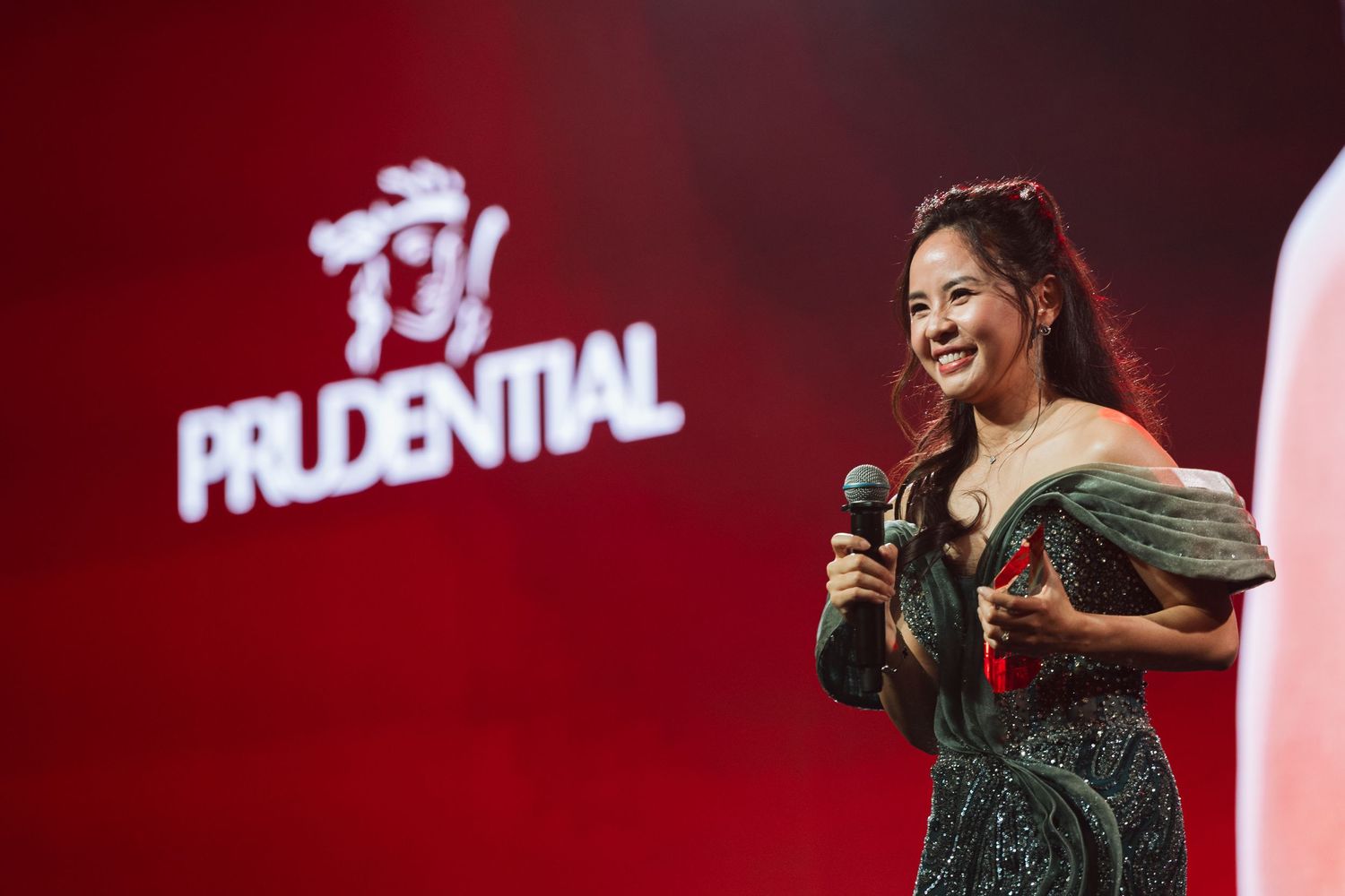 Prudential Agency Awards Night 2026 - Event Videography & Photography - Woman award winner in green sequin dress speaks on stage.