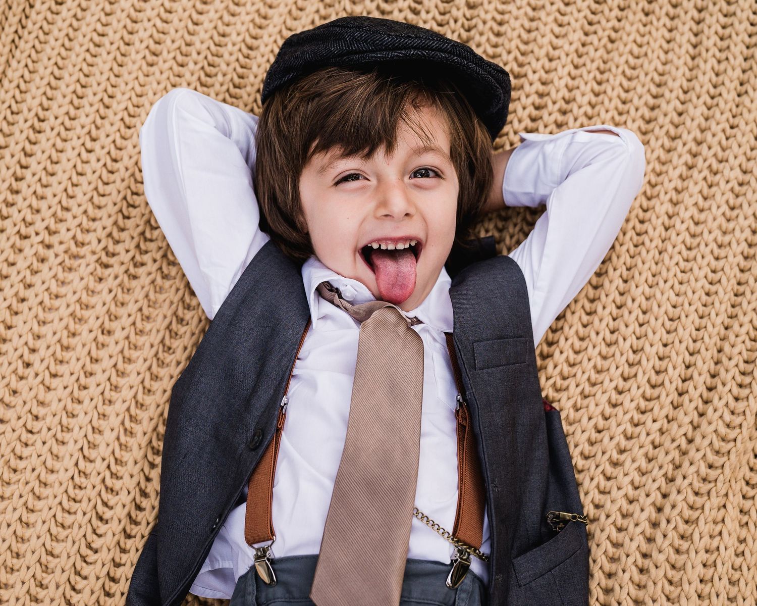 Boy laying on chunky knit blanket with hands behind his head. Illustrates how patterns bring interests to photos. Doughman Photography.