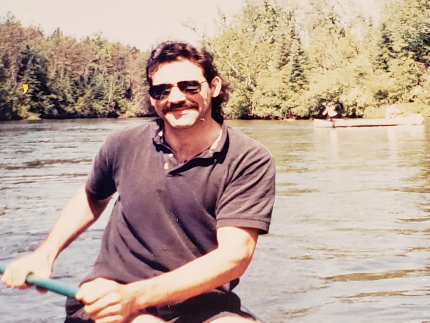 Photographer's father canoeing on a river in Michigan. Tall trees are on either side of the river. About Me Image. Doughman Photography
