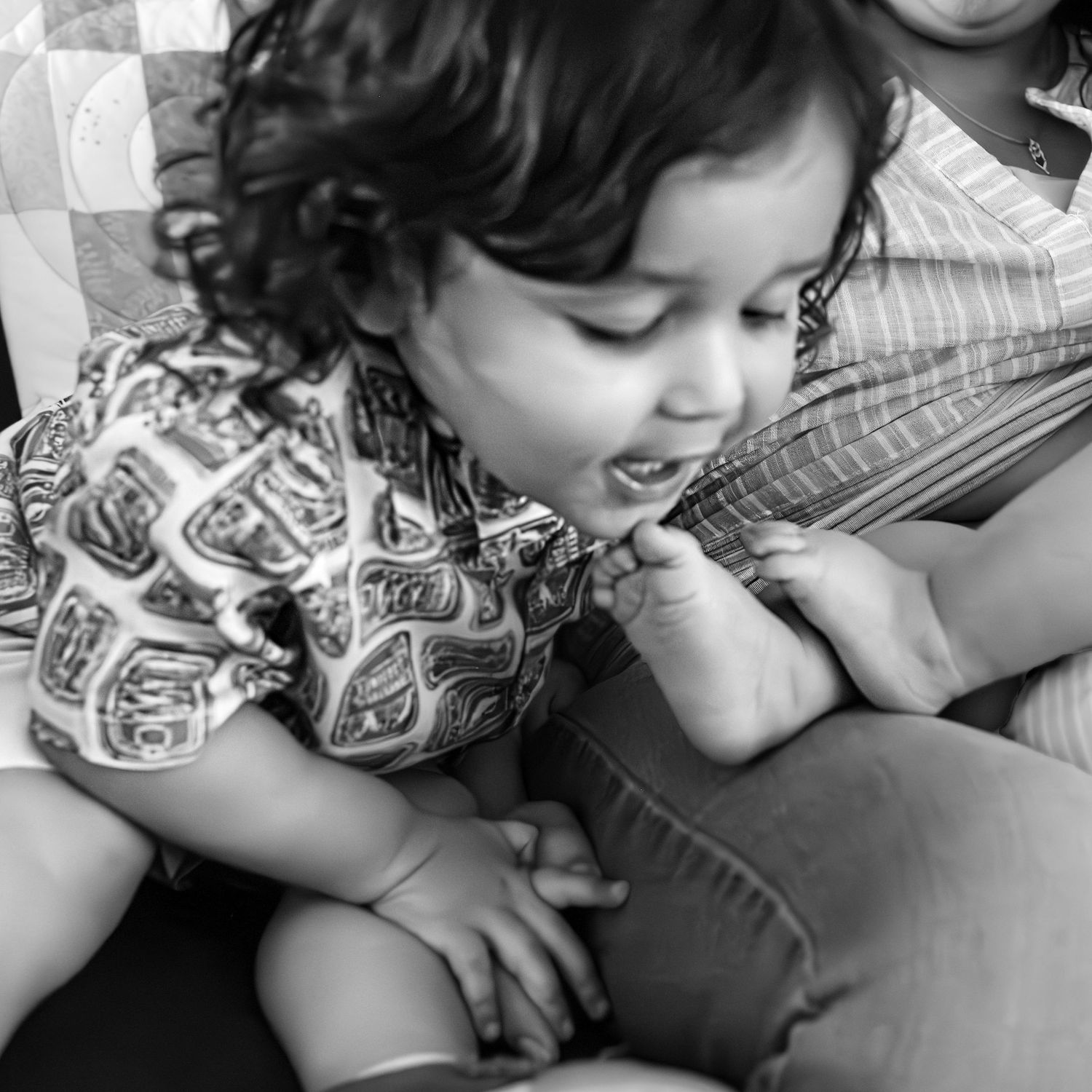 Young brother leaning toward his baby sister's toes