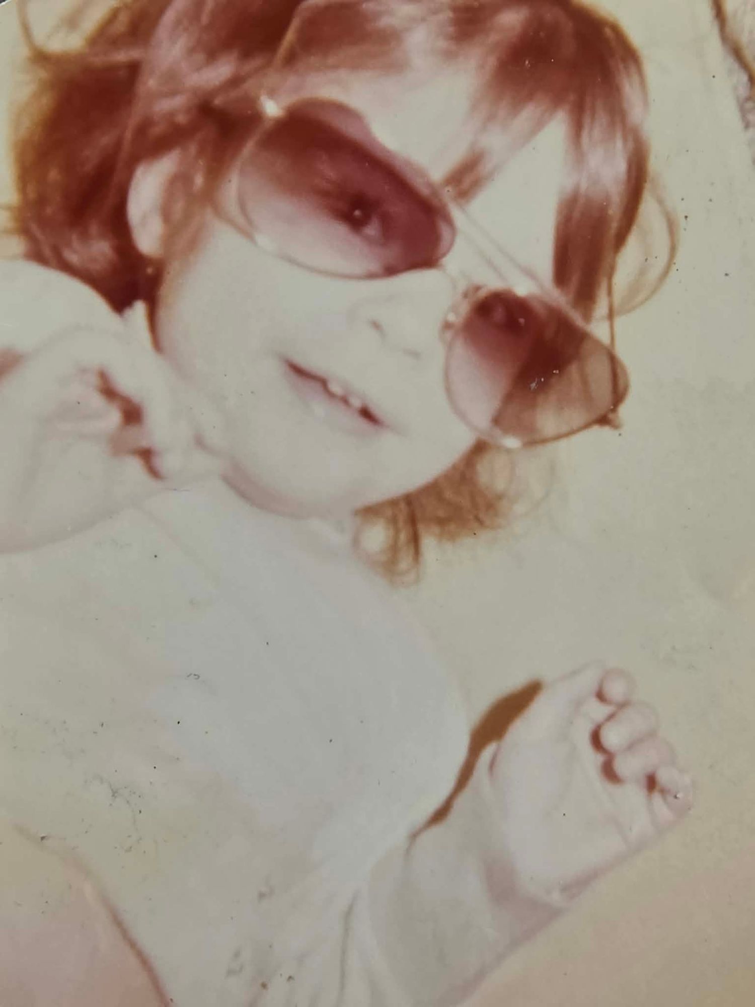 Child wearing oversized sunglasses in an old family photograph
