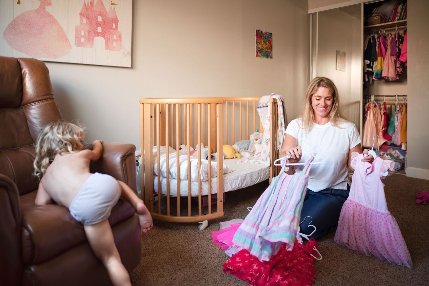 Mother and toddler daughter deciding what dress the daughter will wear.