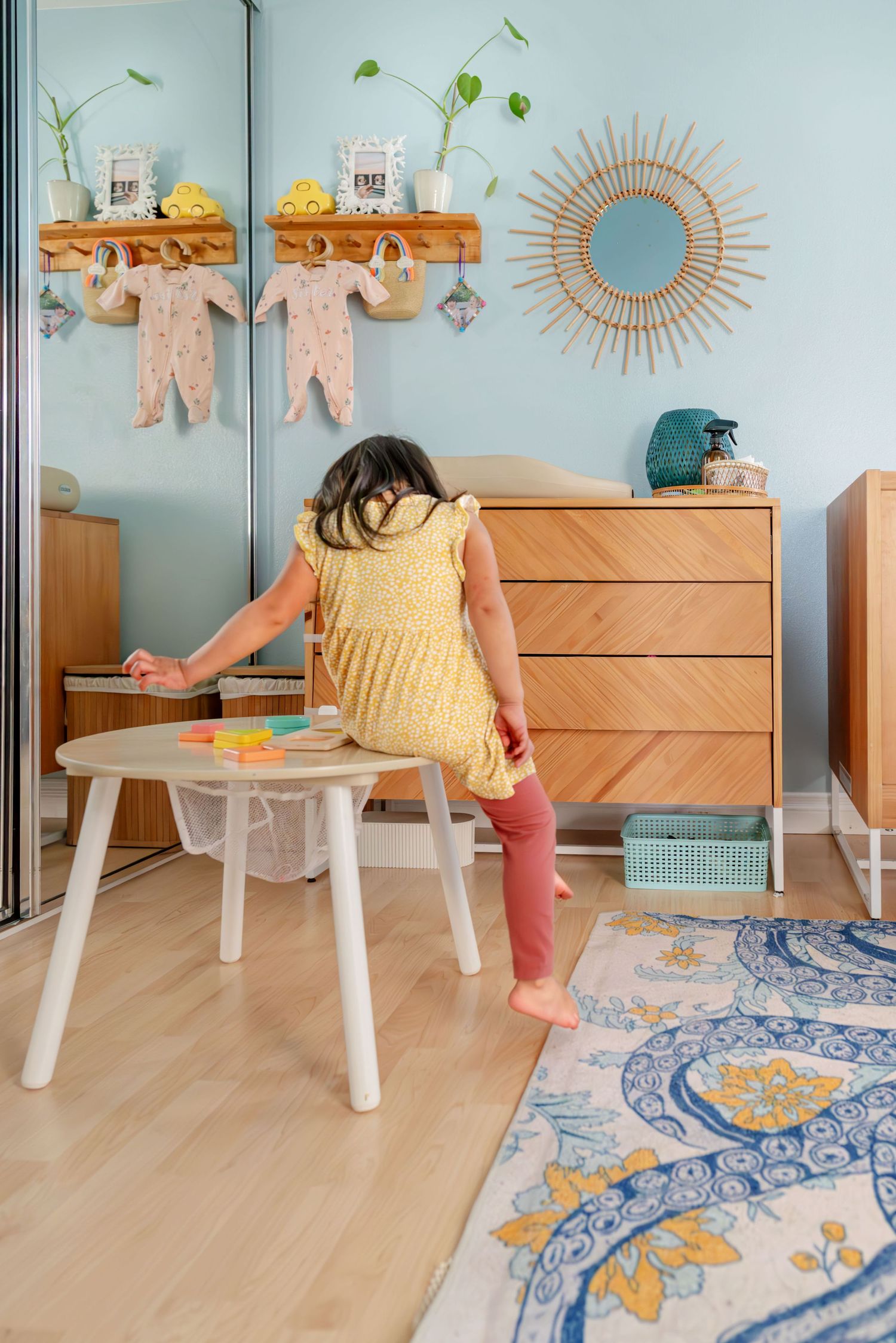 Toddler with her back to the camera as she sits on her play table looking at her toys. Doughman Photography.