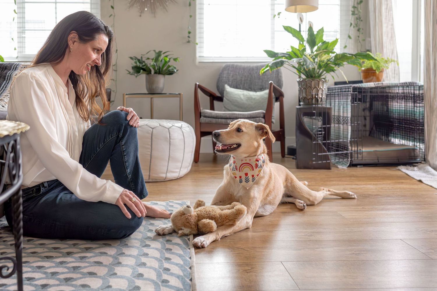 Woman sitting on the floor with her dog in a bright room with lots of plants. Doughman Photography